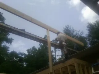 Carpenter setting a ridge beam over a new addition frame — Ice Dam Removal by Roofing Brothers in Dorr