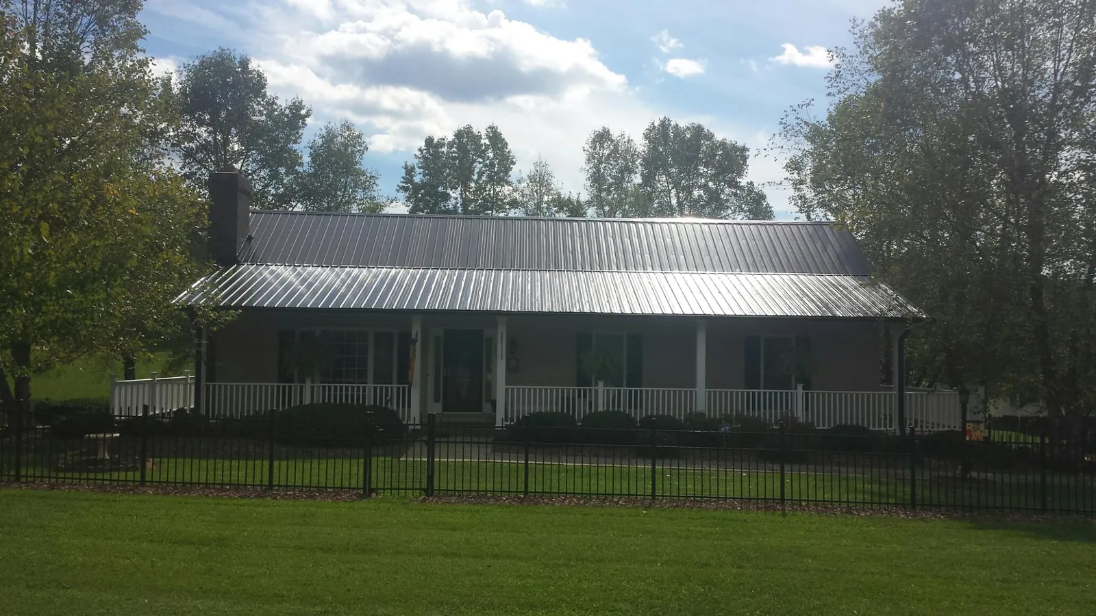 Gray metal roof on a brick ranch with a full width front porch — Gutter Guard Installation work by our crew in Dorr