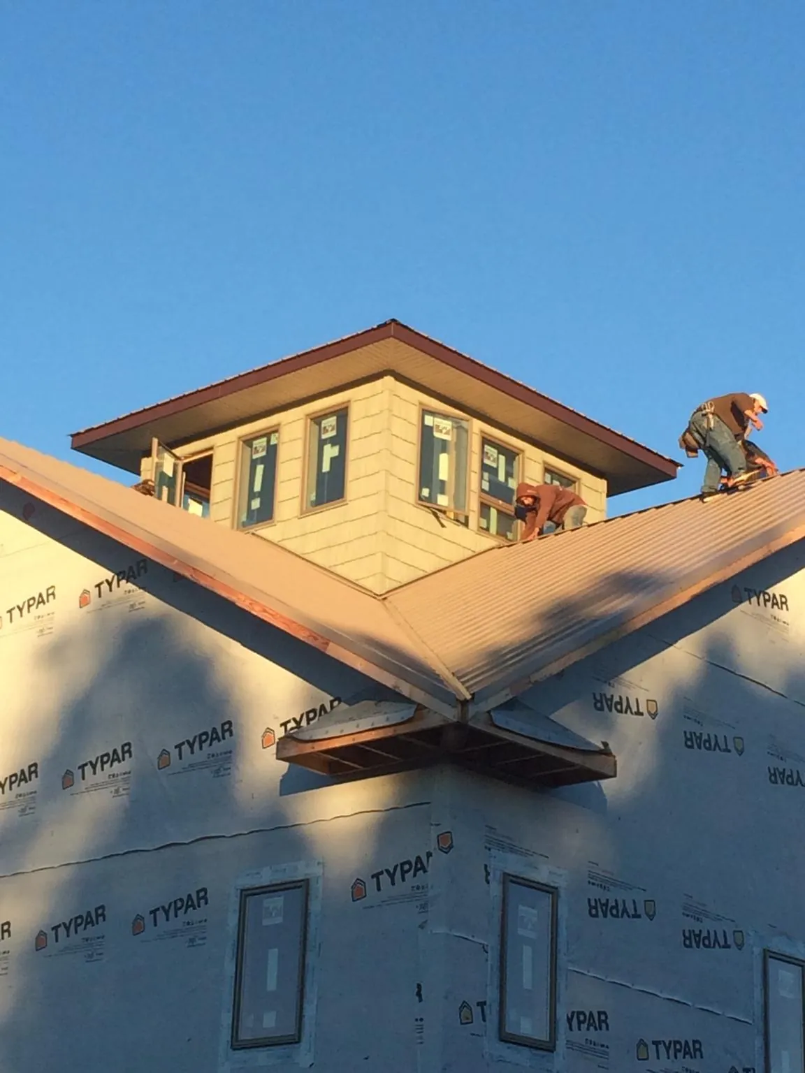 Roofers working around a rooftop cupola on a new metal roof at sunset — Roof Waterproofing in Dorr by Roofing Brothers